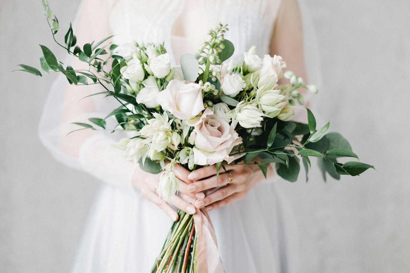 Person holding a bridal bouquet of roses and foliage.
